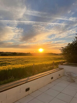 Atardecer sobre un campo con un edificio en primer plano.