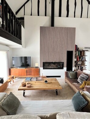 Una sala de estar moderna con chimenea, televisión y estantería.