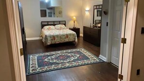 Quarto com cama, penteadeira, mesa de cabeceira e tapete.