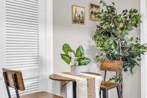 A dining area with a table, chairs, a potted plant, and two framed pictures on the wall. - Hidden Gem!  3BR Family home w/ Fire Pit & Games (St. Augustine)