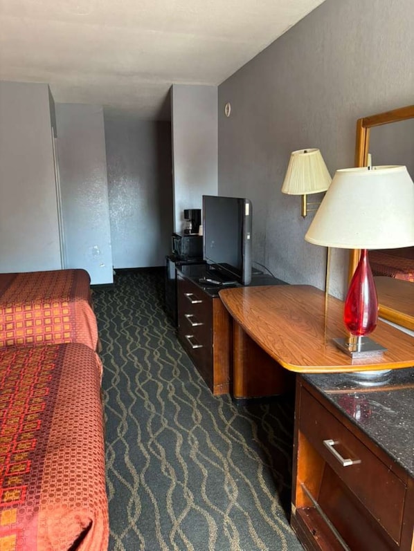 A hotel room with a bed, a desk, a television, and a lamp. - Riverfront Inn (Lemoyne)