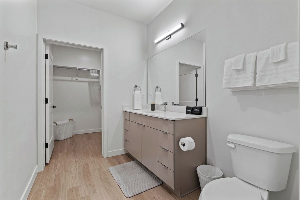 A modern bathroom with a toilet, sink, mirror, and towel rack.