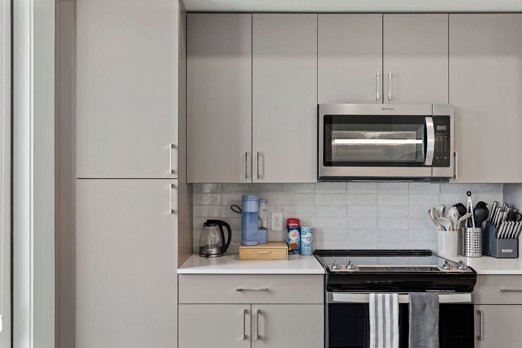 A modern kitchen with a built-in microwave, a coffee maker, and a kettle on the countertop.