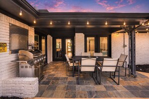 Eine Terrassengruppe mit Grill, Sitzgelegenheiten und einer Ziegelwand.