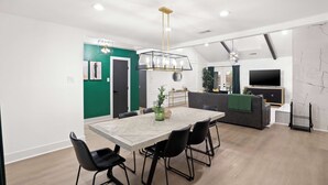 Een moderne keuken met een eethoek, een televisie en een groene accentmuur.