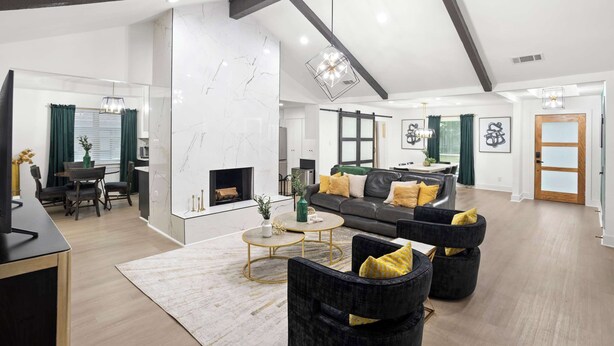 Een moderne woonkamer met een open haard, een zithoek en een eethoek met tafel en stoelen.