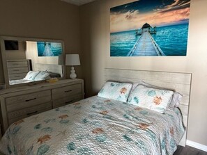 A bedroom with a bed, a dresser, a mirror, and a painting of a pier. - Last minute discount for July 4th week 3-bedroom condo in North Wildwood (North Wildwood)