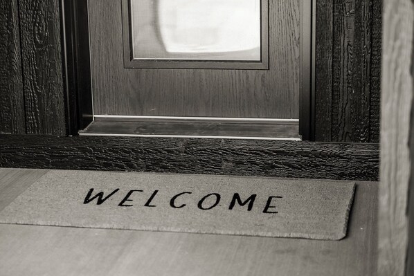 A wooden door with a welcome mat at the entrance.
