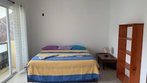 A bedroom with a bed, pillows, a nightstand, a lamp, and a wooden wardrobe. - BRISAMAR GUESTHOUSE (Puerto Escondido)