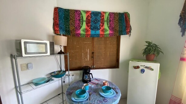 A compact kitchen with a microwave, coffee maker, and a small refrigerator. - BRISAMAR GUESTHOUSE (Puerto Escondido)