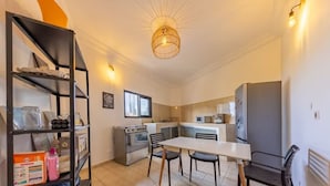 Una cocina compacta con una mesa, sillas, estufa y refrigerador.