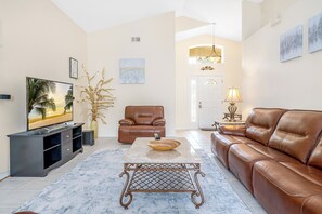 A living room with a sofa, a television, a coffee table, and a decorative lamp. - Spectacular 3b/2b With Private Pool And Spa (Davenport)