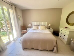 A bedroom with a large bed, a nightstand, a chair, a dresser, and a view through a glass door. - Air-conditioned villa with heated pool - Golf de Pont-Royal - 6 pers (Mallemort)