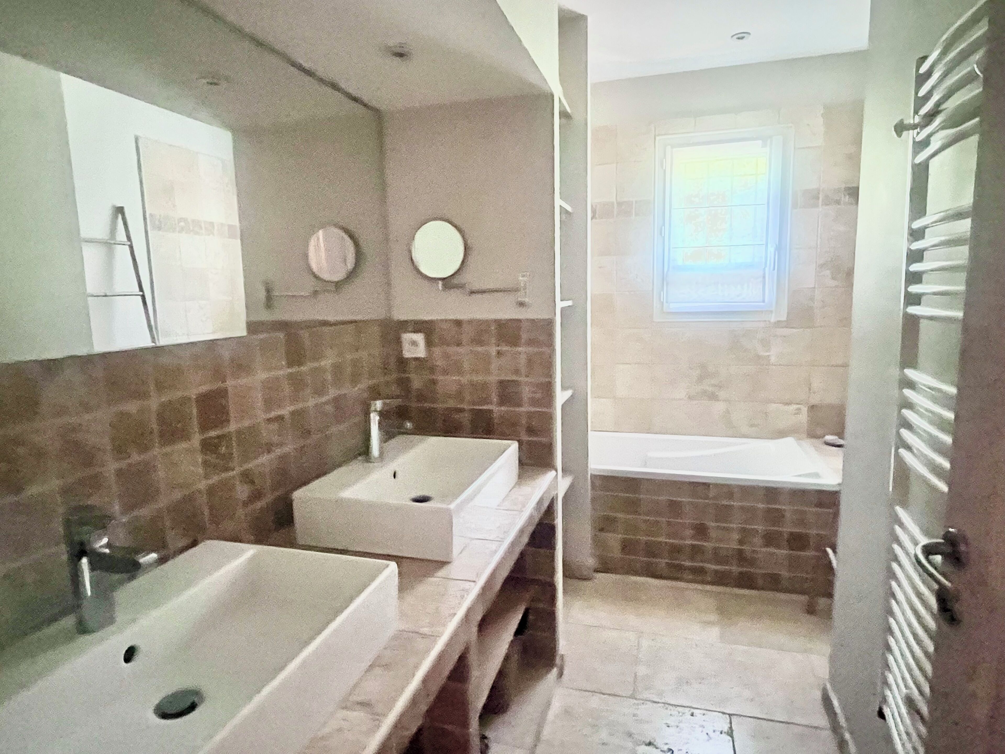 Un baño con dos lavamanos, un espejo, toallero y zona de ducha.