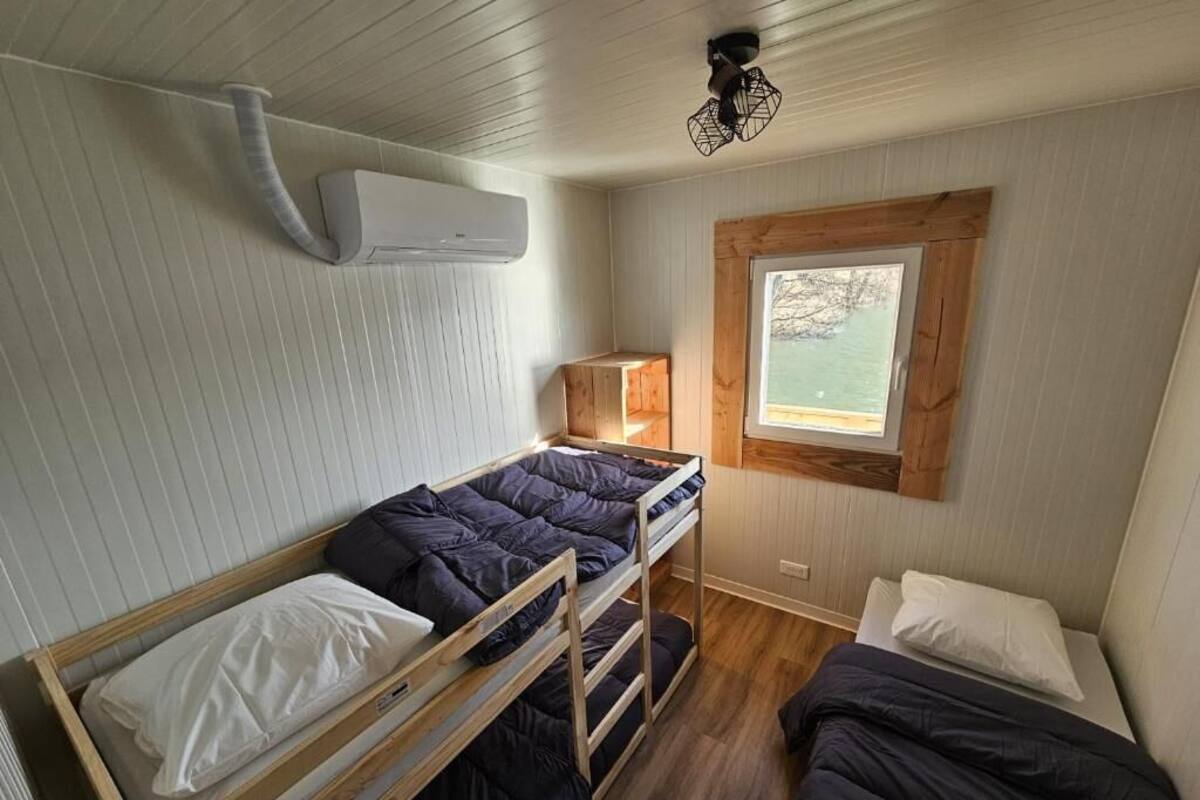 Et lille værelse med køjesenge, et vindue med udsigt og en aircondition.