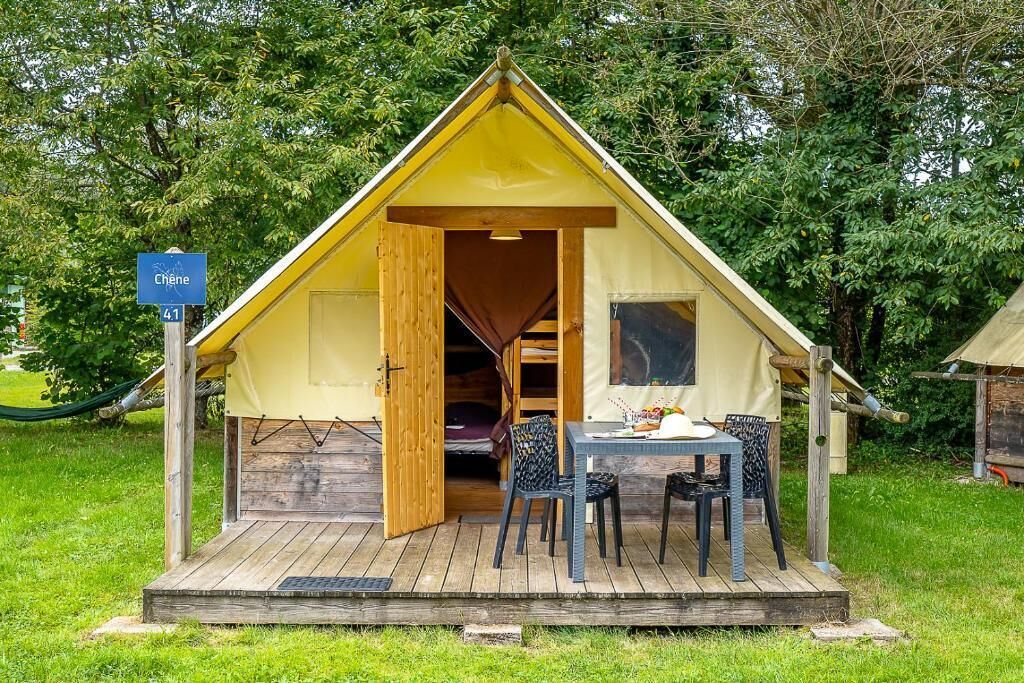 A small, yellow, A-frame tent with an open door, a table with chairs, and a sign indicating the name 'Chene' and route number 41.