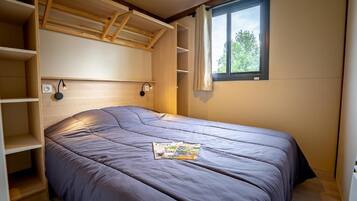 A bedroom with a bed, built-in shelving, a window, and a wall-mounted reading light.