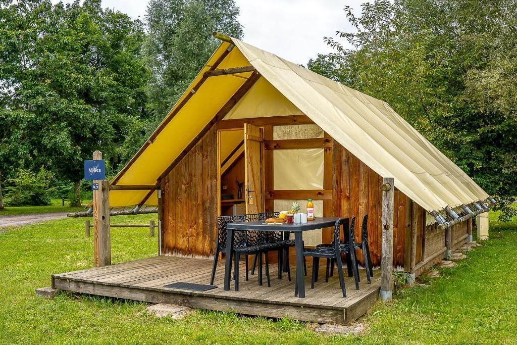 Une cabane en bois avec un toit jaune, une table avec des chaises et un panneau indiquant le numéro 45.