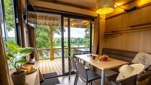 Habitación con una mesa de madera, sillas, un sofá, una planta en maceta y vistas al exterior.