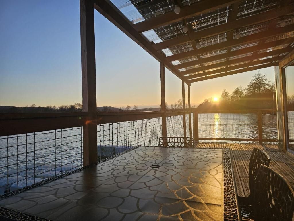 A covered outdoor area with a view of a body of water and a sunset.