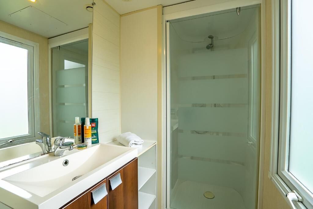 A bathroom with a white sink, mirror, and glass shower enclosure.