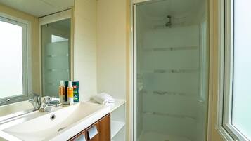 A bathroom with a white sink, mirror, and glass shower enclosure.