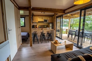 A modern interior with a kitchen, dining area, and a cozy seating space. - Camping Les Ballastières - Vosges du Sud (Champagney)