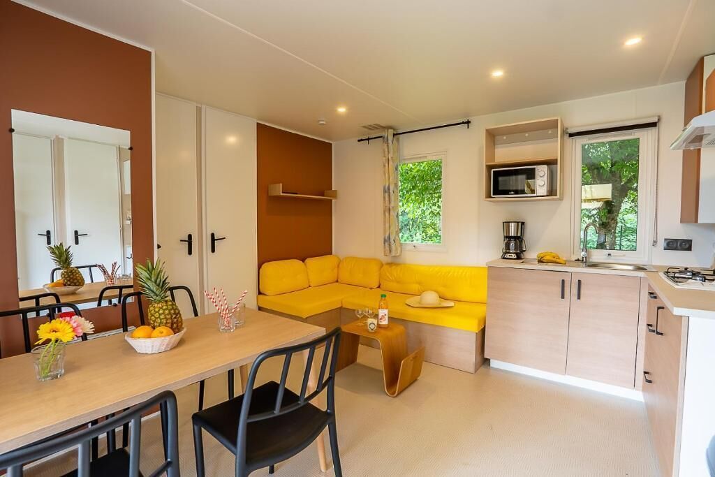A compact kitchen with a dining area, a yellow sofa, and a microwave.
