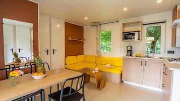 A compact kitchen with a dining area, a yellow sofa, and a microwave.