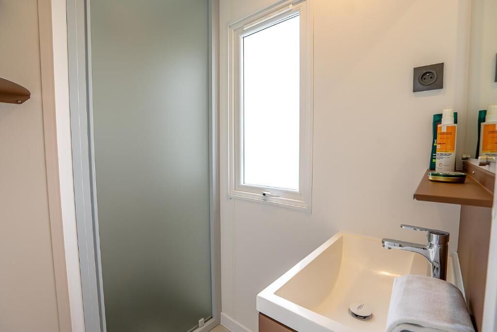 Ein Badezimmer mit Dusche, Waschbecken und Fenster.