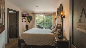 A bedroom with a bed, a nightstand, a lamp, a painting, and a view of the outdoors. - Jacques de Molay Suite with balcony and river view (Dornes)