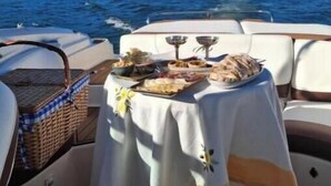 A boat with a table set for dining, surrounded by water and hills. - Jacques de Molay Suite with balcony and river view (Dornes)