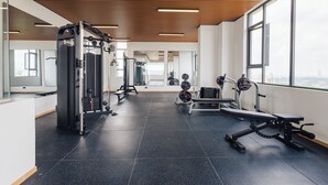 Une salle de sport équipée de matériel d’exercice, dotée de grandes fenêtres et d’un sol carrelé.