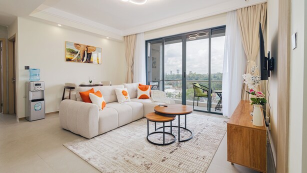 Un salon moderne avec un canapé, une table basse, un distributeur d’eau et un balcon offrant une vue agréable.