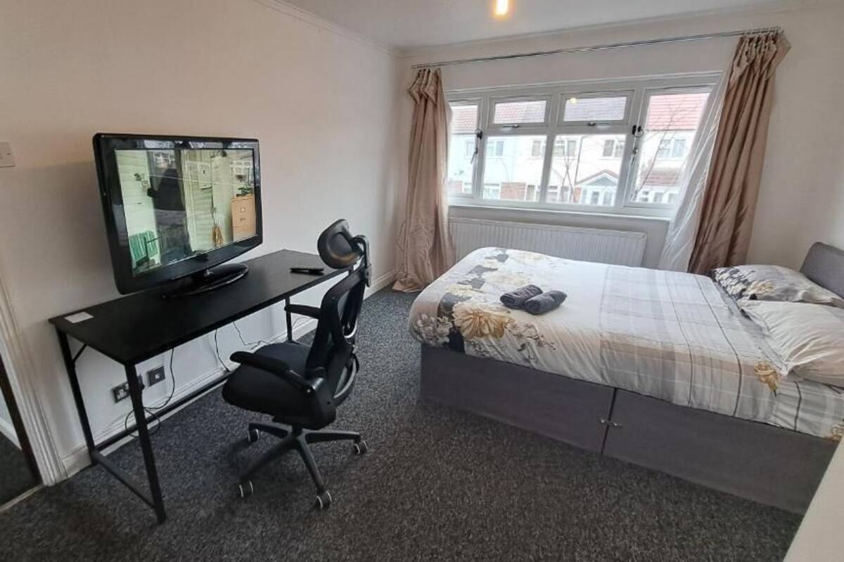 A bedroom with a bed, a desk with a computer, and a chair.