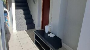 A hallway with a staircase, a reception desk, and a door with an emergency exit sign. - Fenia Estate (Barking)