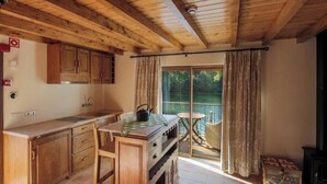 Una cocina de madera con comedor, un ventanal y vistas al verdor.
