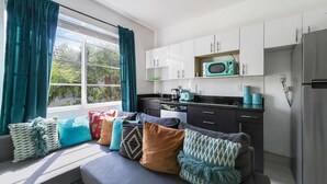 A modern kitchen with white cabinets, a microwave, and a refrigerator. - Drexel Apts by At Mine Hospitality (Miami Beach)
