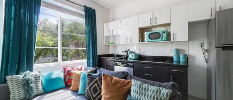 A modern kitchen with white cabinets, a microwave, and a refrigerator.