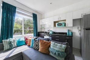 A modern kitchen with white cabinets, a microwave, and a refrigerator. - Drexel Apts by At Mine Hospitality (Miami Beach)