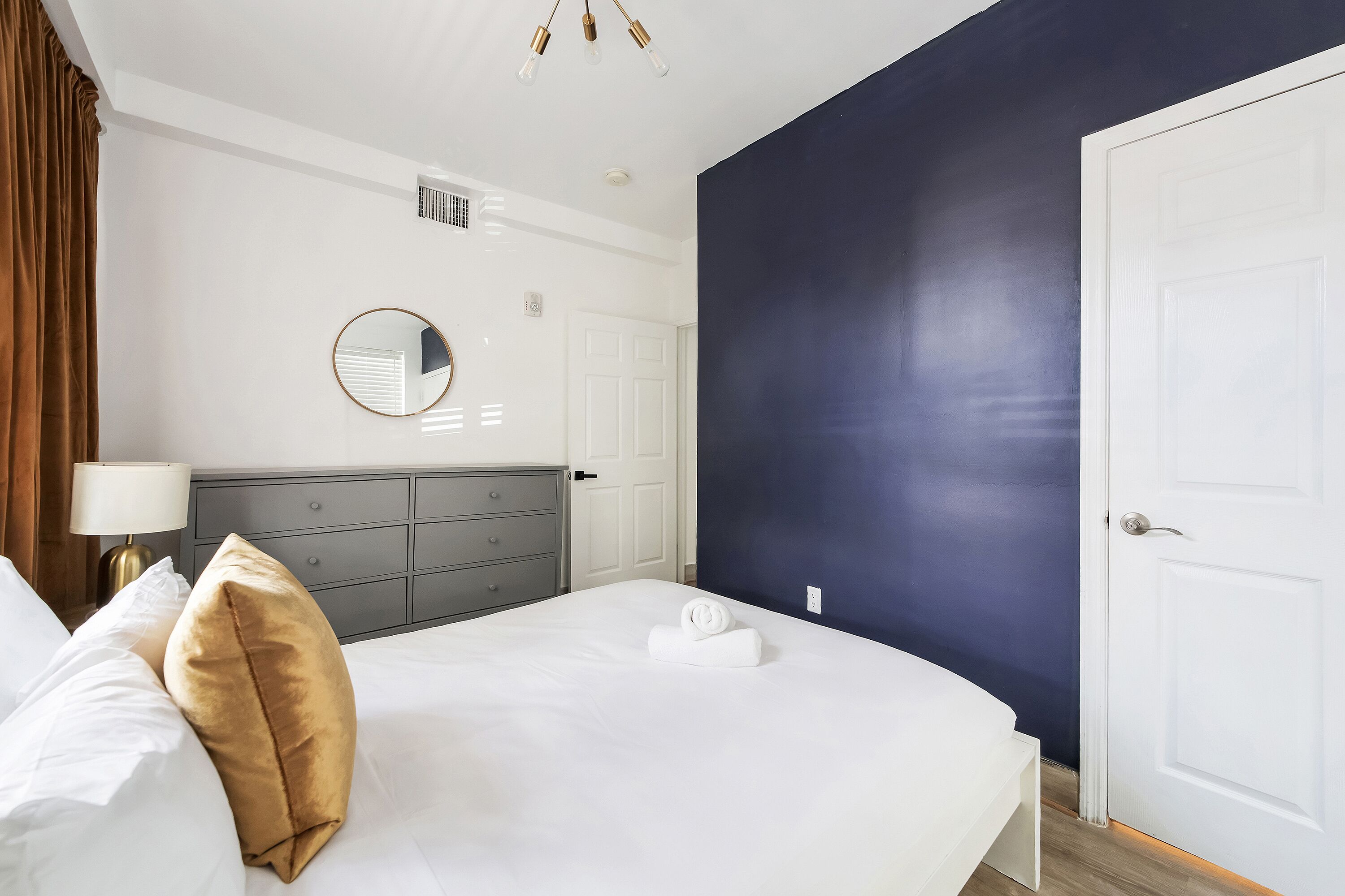 Una habitación de hotel con cama, cómoda, espejo y puerta.