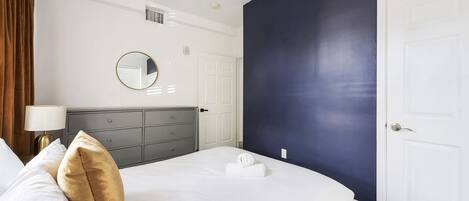 Una habitación de hotel con cama, cómoda, espejo y puerta.