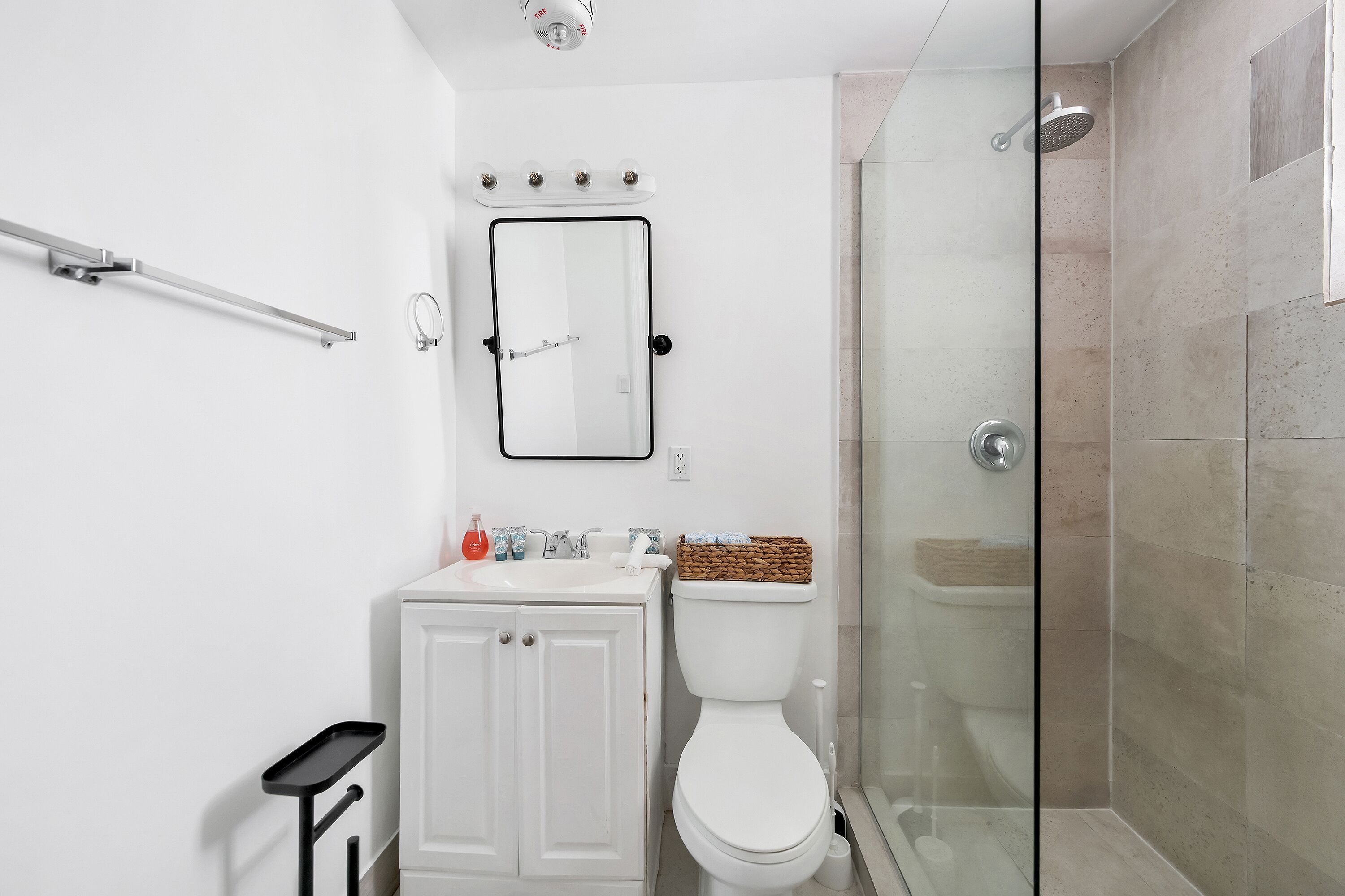 Une salle de bain moderne avec une douche à parois de verre, un lavabo blanc et des toilettes.