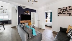 A modern living room with a grey sofa, a black sofa, and a dining area with a table and chairs. - Drexel Apts by At Mine Hospitality (Miami Beach)
