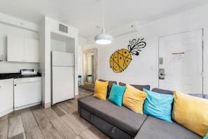 A modern kitchen with white cabinets, a built-in oven, and a dining area with a table and chairs.
