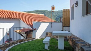 A courtyard with a white table and bench, a red-tiled roof, and a wooden fence. - D. Dinis "O Lavrador" House - Garden and river view (Dornes)