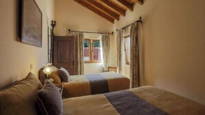 A room with two beds, a lamp, a window with curtains, and a wooden ceiling. - D. Dinis "O Lavrador" House - Garden and river view (Dornes)