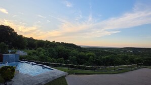 Une piscine entourée d’une terrasse, avec une vue sur un paysage vallonné et un ciel dégagé.