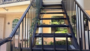 Un immeuble à plusieurs étages doté d’un escalier central, d’un balcon orné de balustrades et d’une grande fenêtre en arc de cercle.