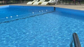 A clear swimming pool with lane dividers and lounge chairs in the background.